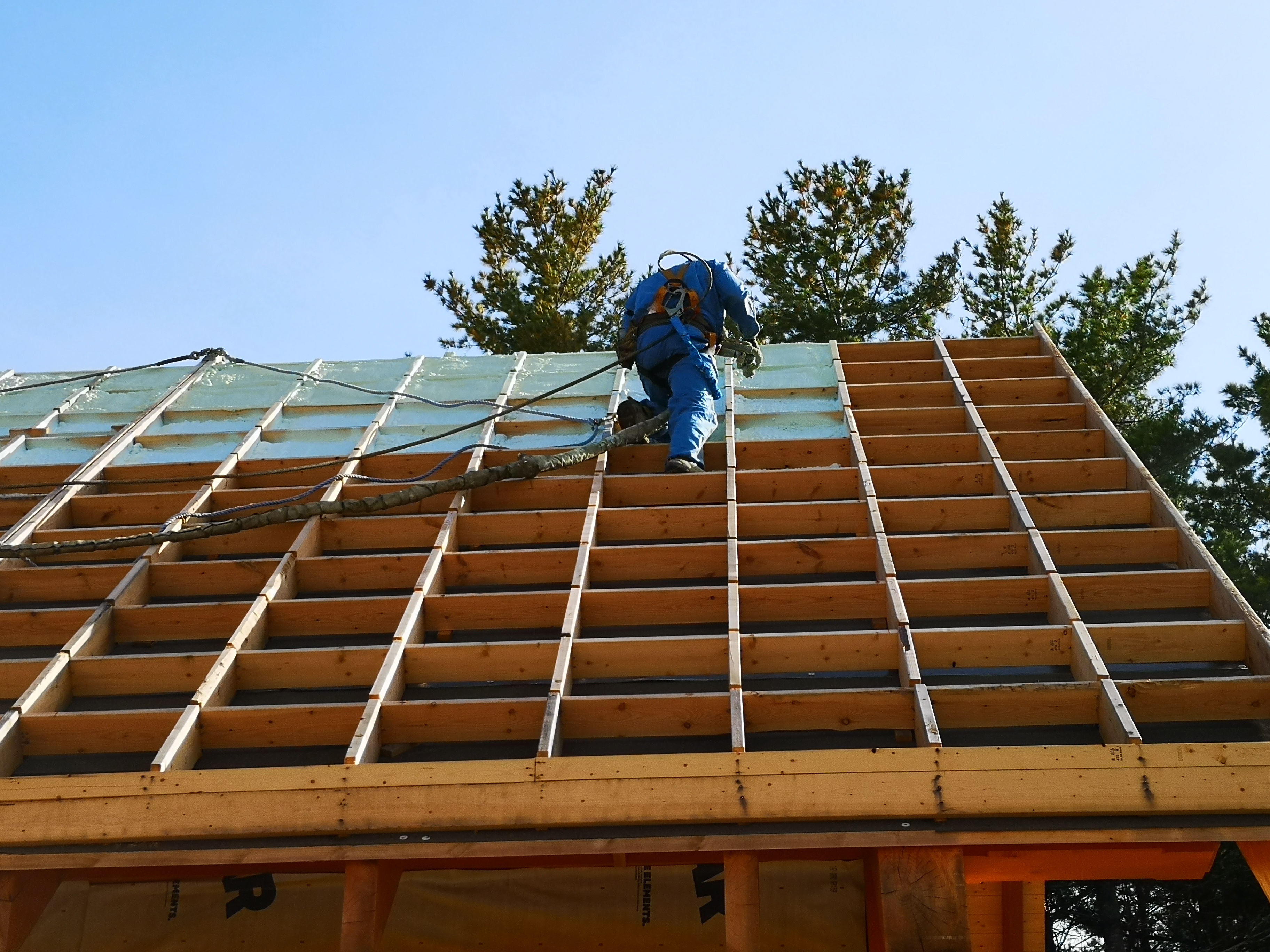 Crew member on roof applying spray foam